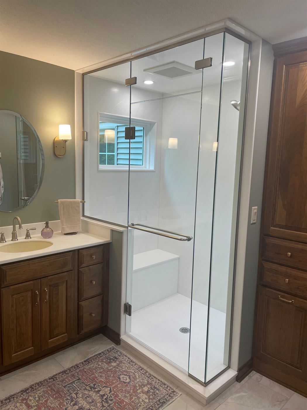 Corner glass shower with bench and vanity by Stellar Construction