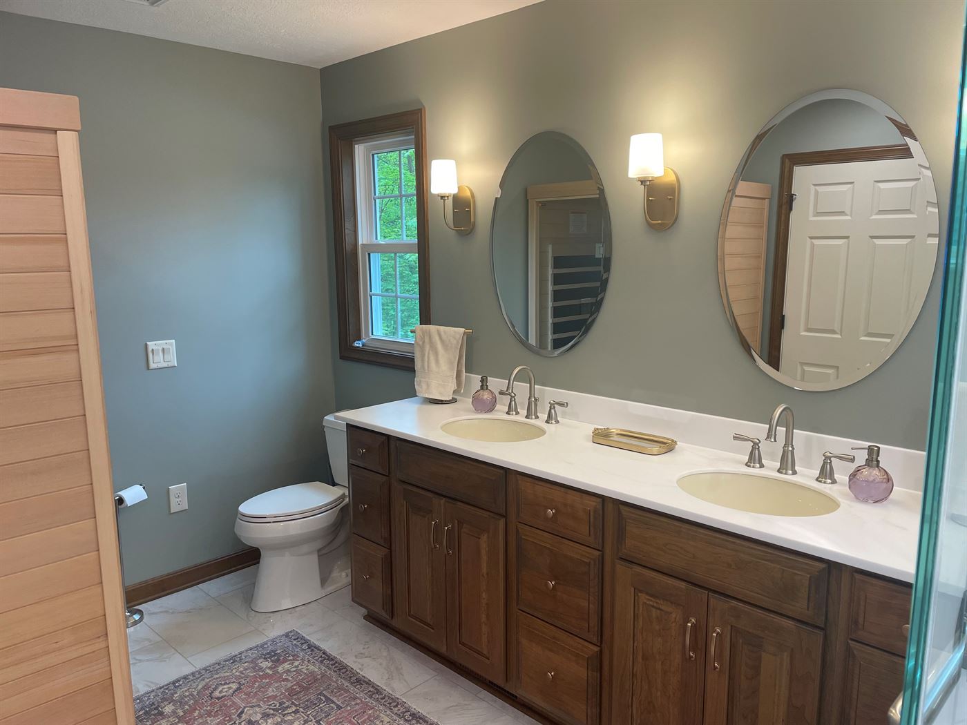 Master bath remodel with double vanity and oval mirrors by Stellar Construction