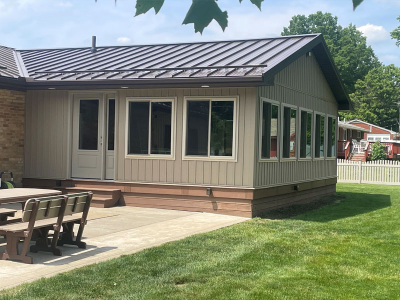 Season room addition with board-and-batten siding and a wall of windows by Stellar Construction