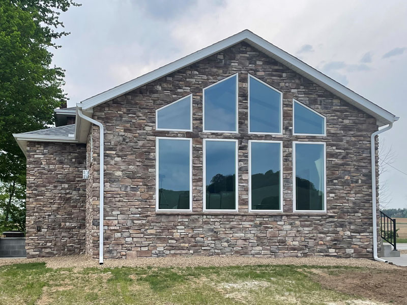 Great room addition with stone exterior and prow window wall by Stellar Construction