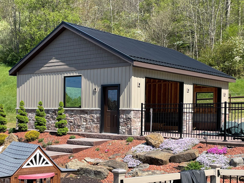 Detached garage with board-and-batten siding, stone base, and metal roof by Stellar Construction